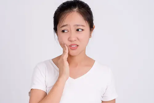 歯の痛みで頬を抑える人