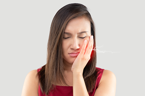 親知らず抜歯後に頬を冷やしてケアする患者のイメージ